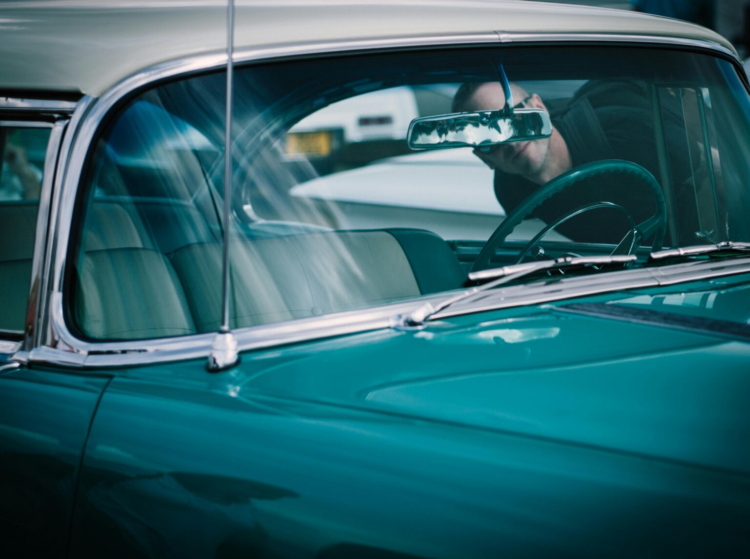 A person sitting in the driver 's seat of an old car.